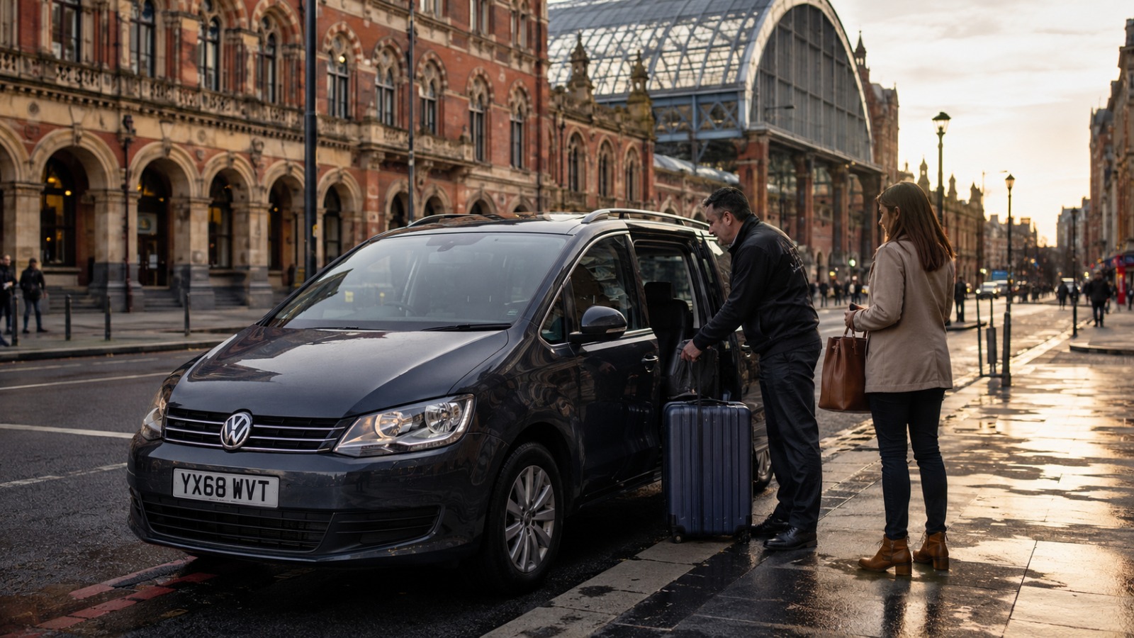 Driver helping a traveller with bags beside a taxi outside a London railway station at dawn